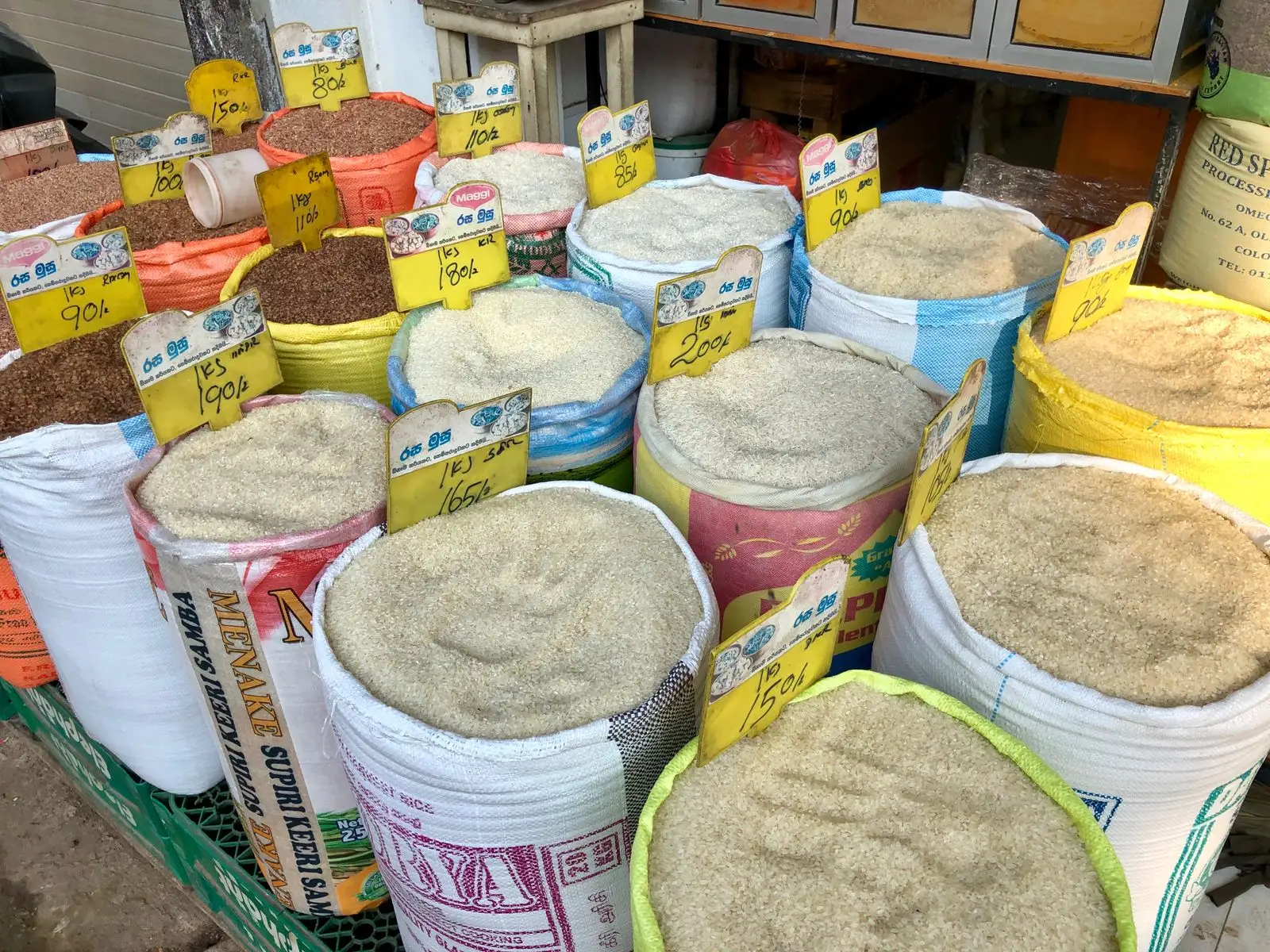 Open PP woven bags of grain and rice in white and bright colours at a market stall